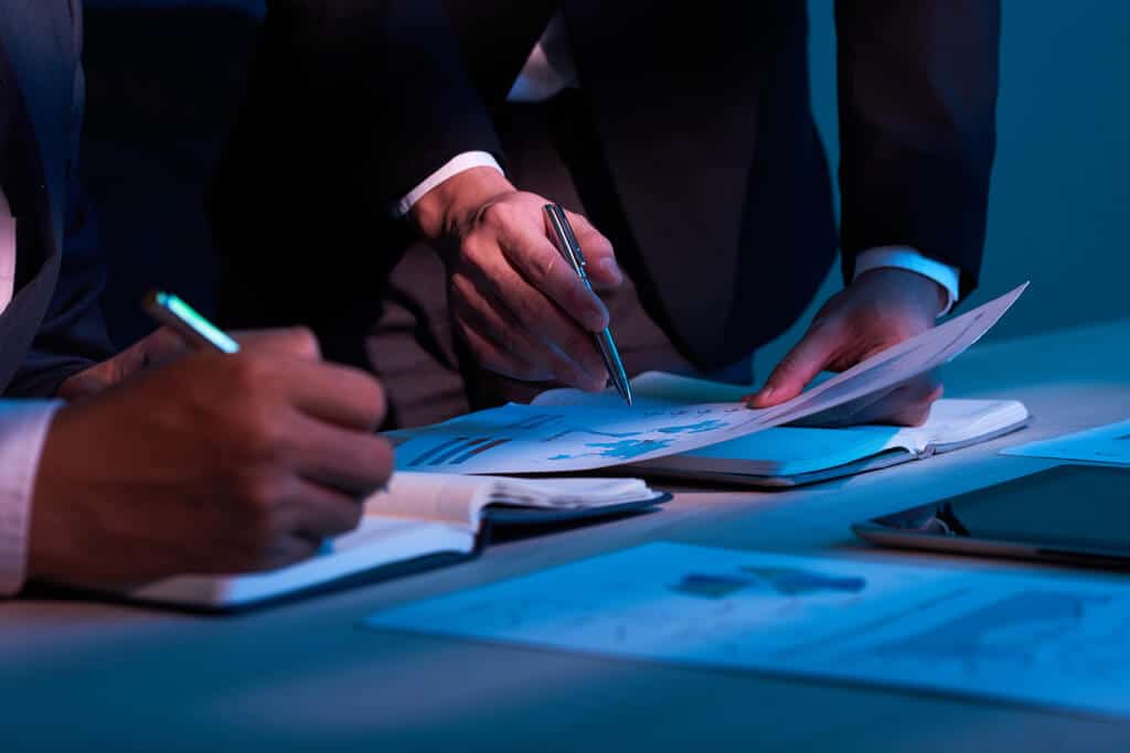 Profissional assinando documentos em análise fiscal e tributária