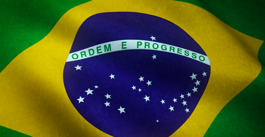 Bandeira do Brasil em close, com o losango amarelo, o círculo azul estrelado e a faixa com a inscrição “Ordem e Progresso”.