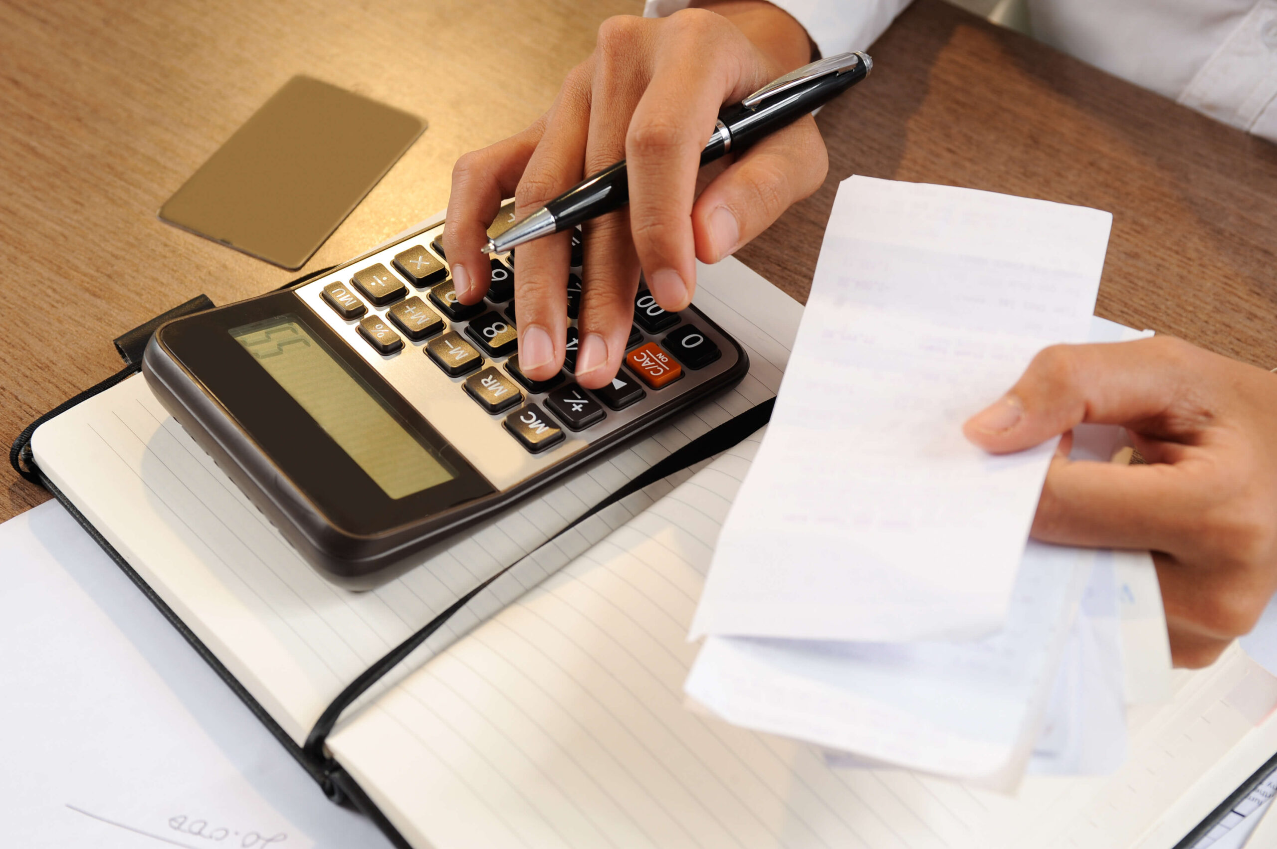 Profissional contábil usando calculadora e analisando documentos fiscais
