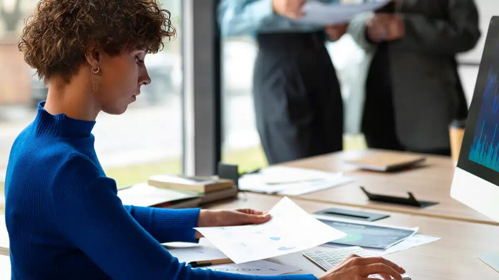 Profissional trabalha em notebook durante reunião no escritório