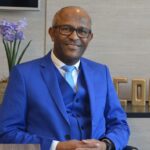 Retrato de homem de terno azul sentado em ambiente corporativo
