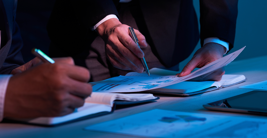 Profissionais analisando relatórios e documentos financeiros em reunião corporativa, realizando auditoria fiscal, planejamento tributário e tomada de decisões estratégicas.