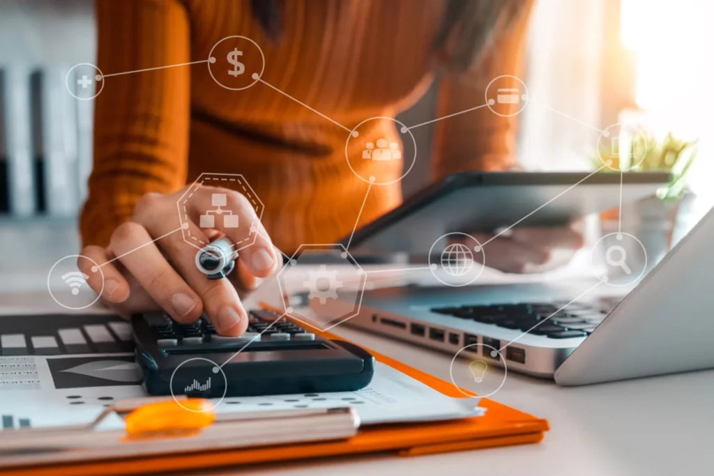 Profissional realizando cálculos financeiros em calculadora e tablet, utilizando tecnologia para gestão fiscal, planejamento tributário e análise de indicadores empresariais.